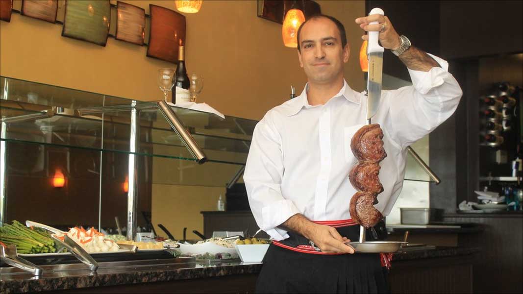 Brazilian waiter displays picanha steaks on a skewer at Brazil Express Grill.